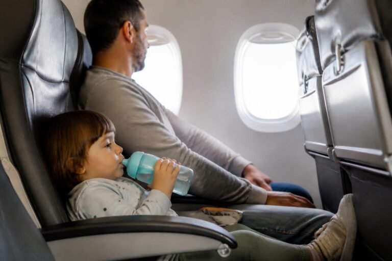 Criança em voo bebendo água durante viagem de avião em família